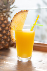 sweet pineapple juice in a glass with pineapple in the background