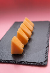 five pieces of melon on a stone slab on a pink background