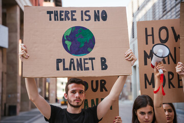 Group of young people at a demonstration for the environment - Young millennials protest at a procession to save the planet with slogans and drawn in the sign - Concept of manifestation - 364042675