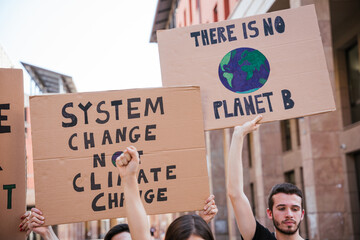 Group of young people at a demonstration for the environment - Young millennials protest at a procession to save the planet with slogans and drawn in the sign - Concept of manifestation