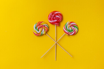 Сolorful lollipop on a yellow background. Delicious round candy