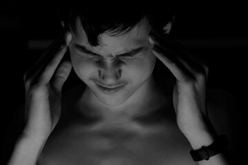Obraz premium Portrait teenager on a black background. Concept of pain and tension