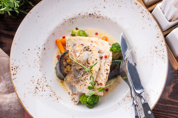 Top view of cod fillet with vegetables on a plate.