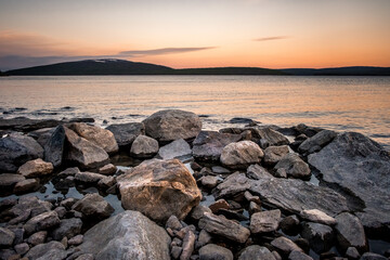 Fototapeta na wymiar Stones on the White Sea coast at sunset. Frozen water, summer, white nights. Murmansk Region, Kola Peninsula, Russia