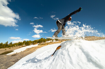 Stylish young girl snowboarder does the trick in jumping from a snow kicker against the blue sky...