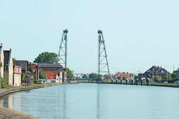 Fototapeta premium Water of the Gouwe Canal with in the background the green steel vertical lift bridge of Waddinxveen in the Netherlands.