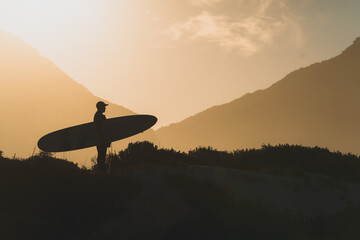 Silhouette of surfer at sunset.