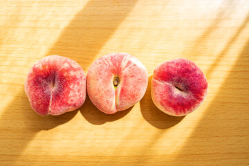 A plate of fresh flat peaches on a wooden table