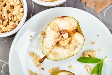 Tasty roast pears with honey and walnuts on white plates on grey background table. Top view.  Flat lay. Copy space.