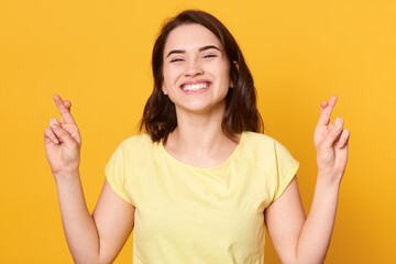 Attractive lady believing dreams come true, hopeful dark haired woman feels lucky, crosses fingers,...