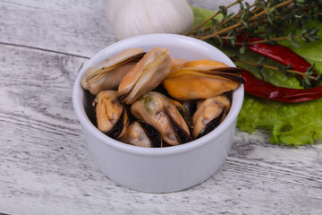 Pickled mussels in the bowl served pepper, garlic and salad