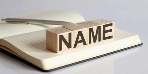 NAME sign on a wooden block on notebook background