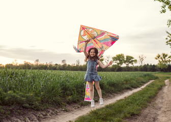 Girl 5 years old with a kite in the field. Child at sunset with a kite.