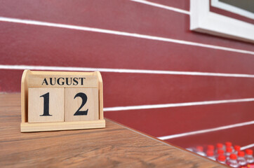 August 12, Number cube with wooden table beside the wall.