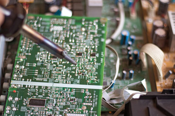 soldering iron positioned in front of printed circuit board.