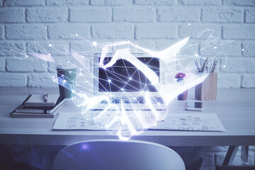 Desktop computer background in office and handshake hologram drawing. Double exposure. Pertnership concept.