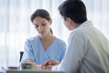 A doctor takes care of a sick patient woman with sadness and unhappiness at the hospital or medical clinic.