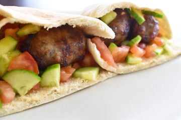 Sheftalia Cypriot Sausages with Fresh Vegetables (Cucumber and Tomato) on a White Plate. Traditional Cypriot food: Cypriot Lamb and Pork Sausages.   