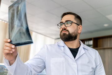 Fototapeta premium Hospital doctor holding patient's x-ray film. Modern office background. Healthcare, roentgen, people and medicine concept.