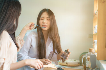 Beautiful asian casual girl is tasting food and smiling while cooking in kitchen