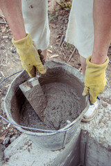 Hands stir the cement in a bucket
