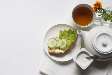 Breakfast in a white bowl on a light background croissant with herbs, vegetables, butter, cheese, herbal, green tea, flower, fruit, yogurt