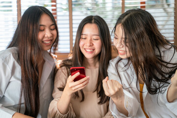 Group of female friends in home office using digital smartphone devices looking together