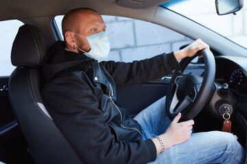 Man with protective mask adriving a car by Coronavirus pandemic quarantine