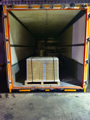 Worker unloading shipment carton boxes and goods on wooden pallet by forklift  from container truck...