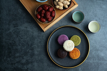 Colorful moon cakes are placed on black plates. Chinese traditional food mid autumn moon cake