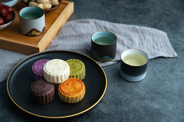 Colorful moon cakes are placed on black plates. Chinese traditional food mid autumn moon cake