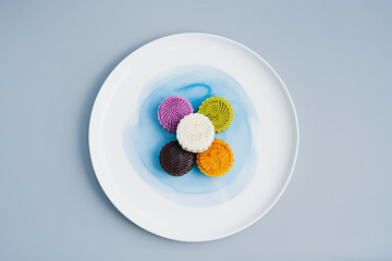 Colorful moon cakes are placed on white plates. Chinese traditional food mid autumn moon cake