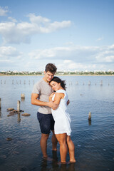 Fototapeta premium Beautiful people in love. The woman put her head on the man's shoulder.A married couple is relaxing at the sea. A woman in a white dress on the beach. Husband and wife walking along the beach. Love. R