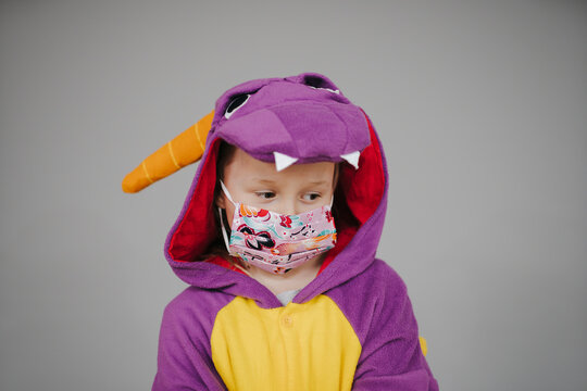 beautiful young girl with nose and mouth mask dressed in dragon costume during corona crisis
