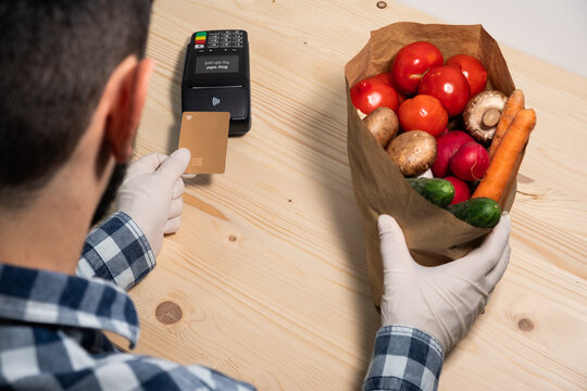 Paying with gold credit card contactless Nfc at POS on virus days on wooden background. Pay with card. Stay save! Nfc pay. Covid pay. Safe pay.