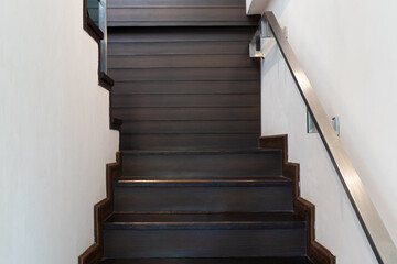 Modern minimalist style stairs with brown wooden and steel handrails.