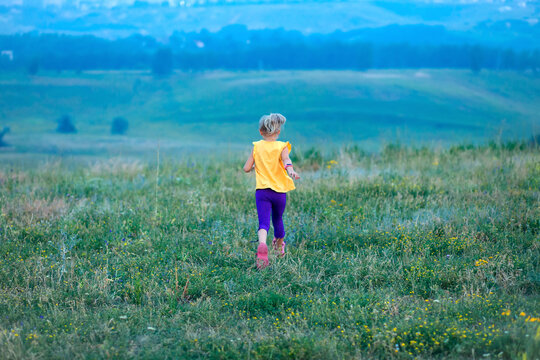 Children run across the field in summer among wildflowers, a sense of freedom, a happy childhood surrounded by nature, hiking, family holidays in the country
