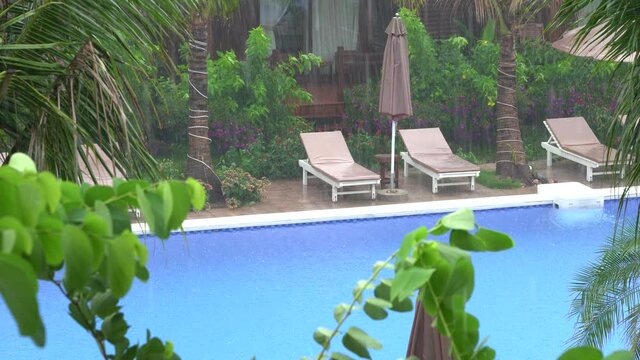 Tropical summer rain falling big rain drops falling down on swimming pool near sea on the beach in Phu Quoc island, Vietnam, Southeast Asia. Concept of nature and the environment