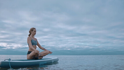 woman performs exercises from yoga on a surfboard. Yoga surf workout