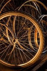 Old rusty bicycle wheels and tires in messy composition in dark room / space. 