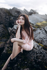 Young brunette girl portrait outdoors in grey mountains outdoors. Woman beauty concept