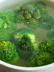 Cooking healthy broccoli vegetable in water in a pot. Closeup, vertical shot