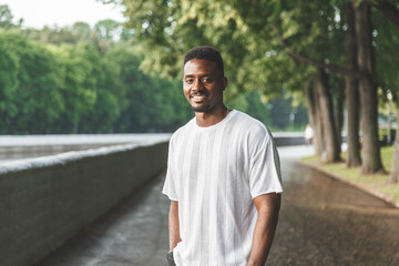 Young man smiling at camera in a park. Horizontally framed shot.
