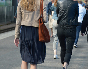 Female commuters walking as part of the crowd on the platform of a train station. Photographed in...