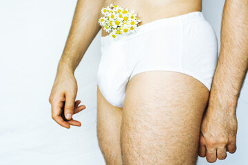 Man in white shorts underwear, male swimwear, shorts, underwear, concept. bouquet of white chamomile daisy flowers