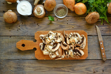Royal champignons in sour cream sauce. Recipe. Step by step cooking mushrooms with onions. Wood background. Top view. Food on a cutting board. Fresh chopped mushrooms.