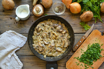 Royal champignons in sour cream sauce. Recipe. Step by step cooking mushrooms with onions. Wood background. Top view. Mushrooms with onions and sauce in a pan