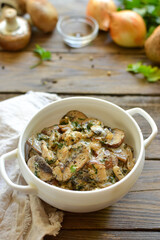 Royal champignons in sour cream sauce. Recipe. Step by step cooking mushrooms with onions. Wood background. Mushrooms with onions and sauce in a white bowl. Vertical view