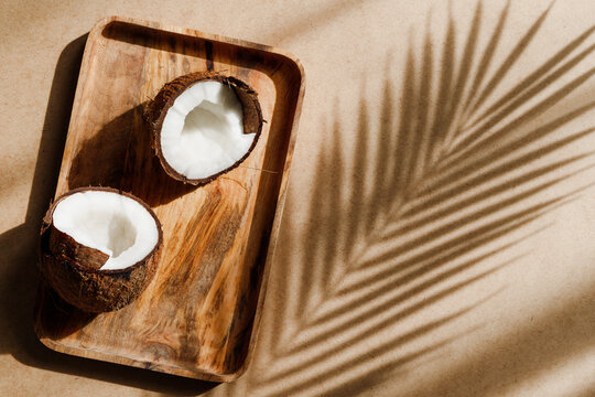 Summer abstract creative composition with coconut a on wooden tray over kraft paper.