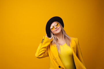 Cheerful trending young woman in bright clothes on yellow background, copy space. Cool blonde